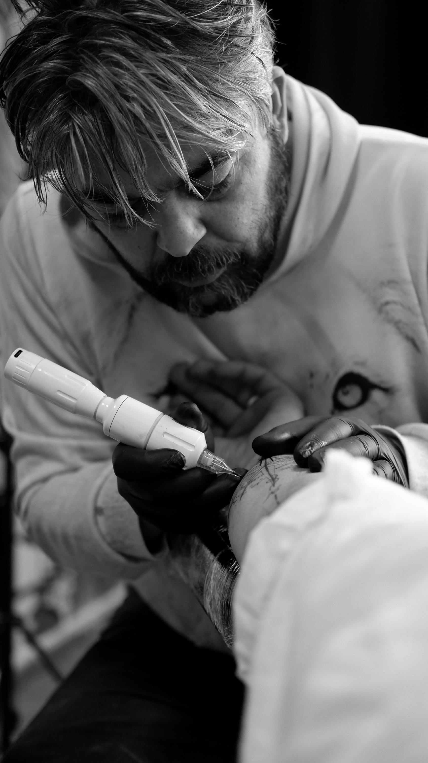 Black and white close-up of a tattoo artist working with concentration in a studio.