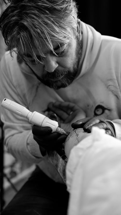 A Tattoo Artist Tattooing an Arm 