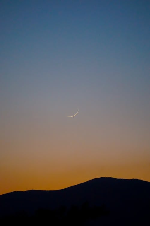 Crescent on Sunset Sky over Hill Silhouette