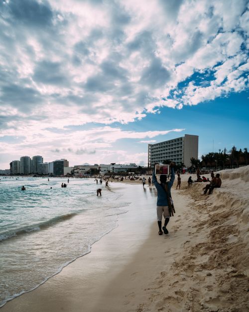 Free Vibrant seaside scene with people enjoying the beach under a cloudy sky. Stock Photo