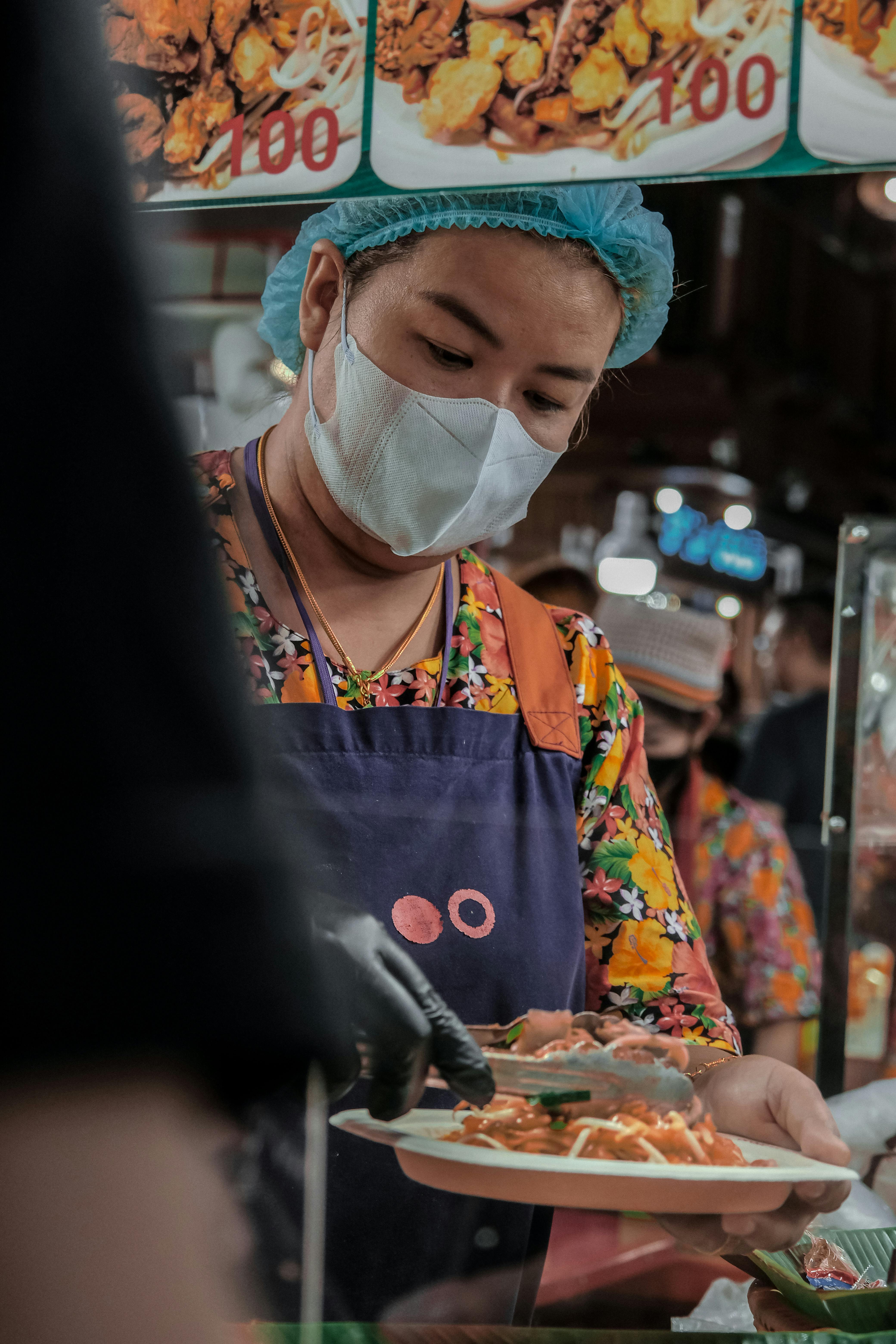 a woman wearing a face mask and a surgical mask is serving food