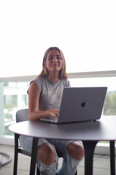 A young woman sits outdoors with a laptop, focused on online learning.