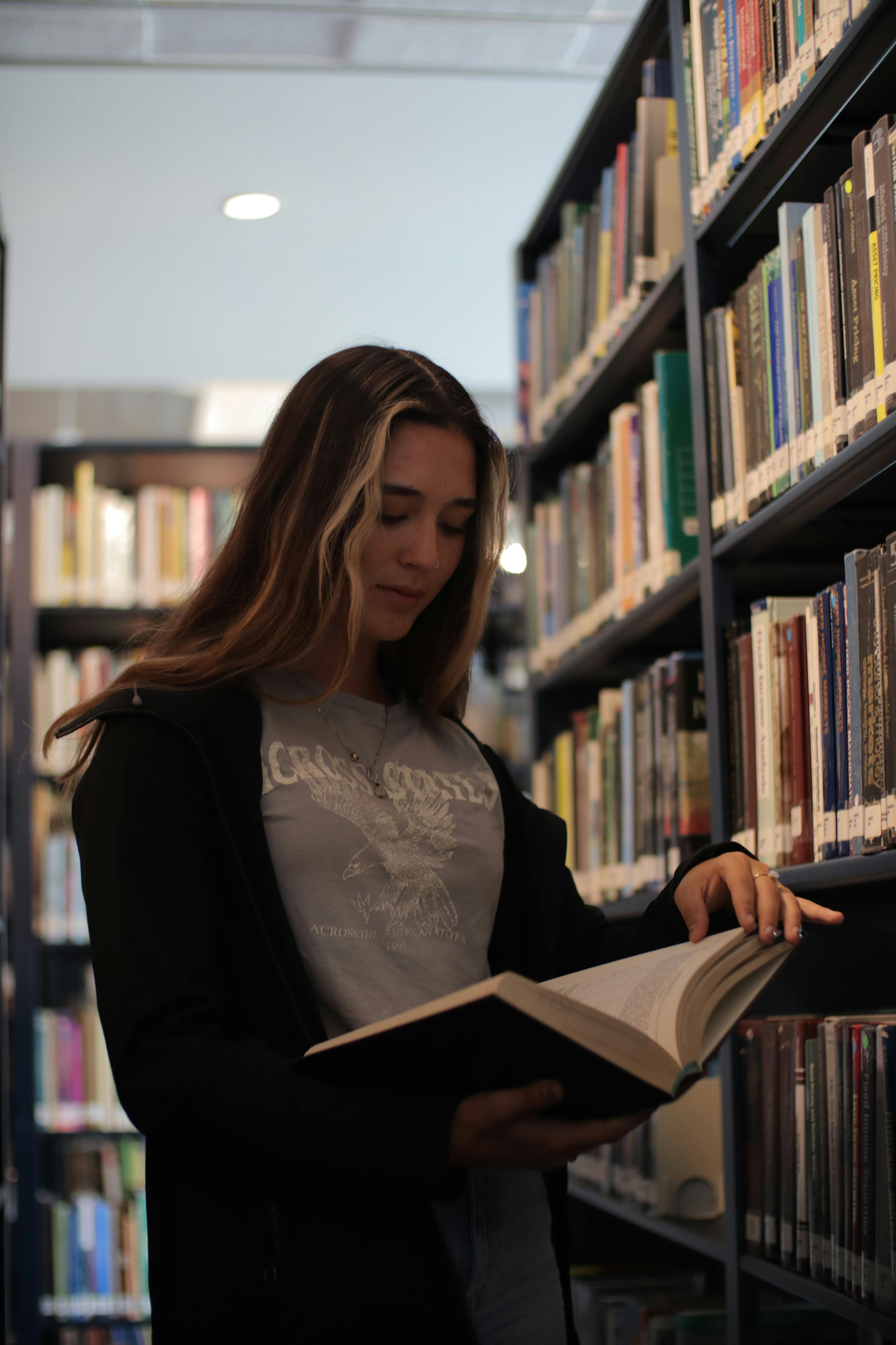 a woman is standing in a library looking at a book