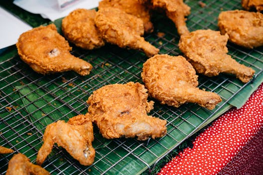 Golden crispy fried chicken served on banana leaves in a Bangkok street market.