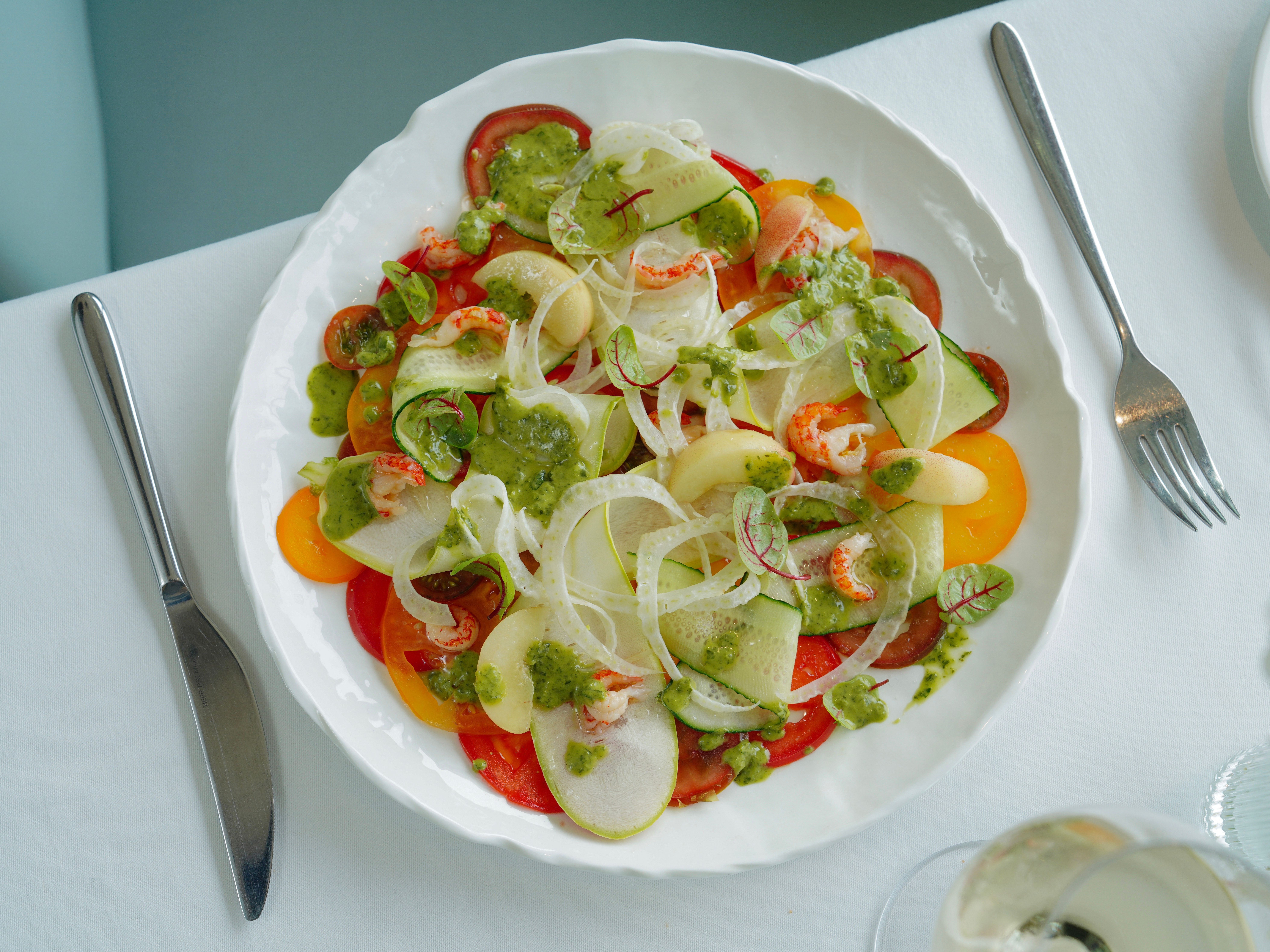 Top view of a colorful fresh vegetable salad with lemon vinaigrette on a table setting.