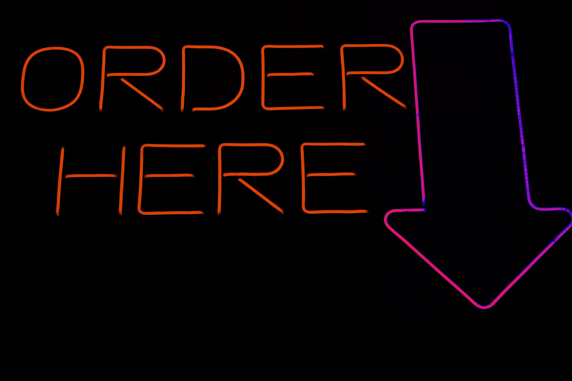 Bright neon 'Order Here' sign with an arrow, perfect for restaurants or cafes.