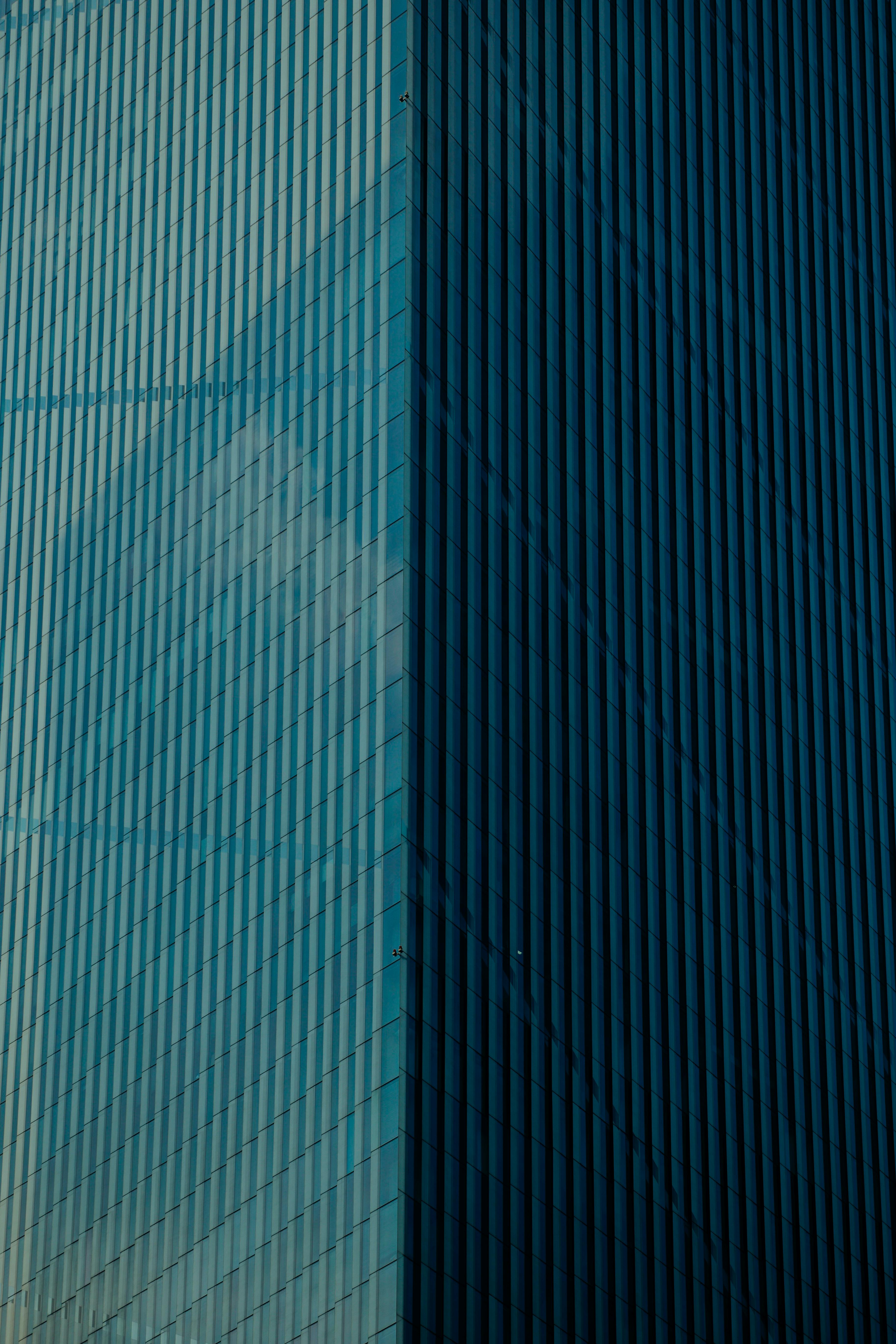 Detailed view of a modern skyscraper's reflective glass facade in urban setting.