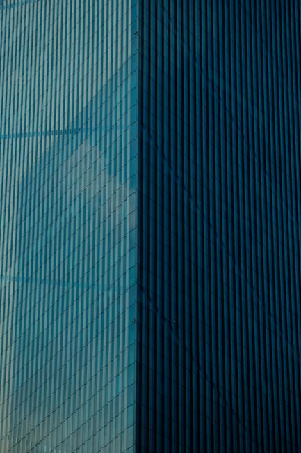 Detailed view of a modern skyscraper's reflective glass facade in urban setting.