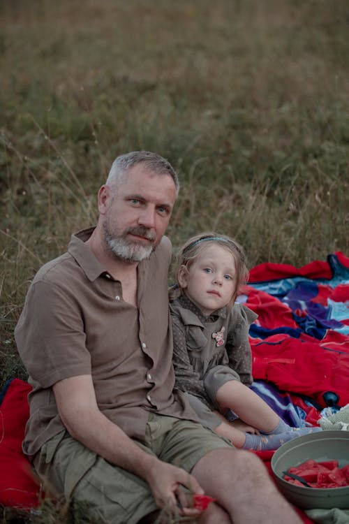 Man Sitting on a Field with His Daughter 