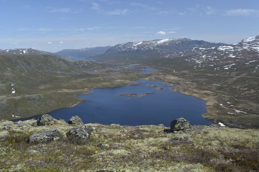 Breathtaking view of a tranquil lake surrounded by snowcapped mountains and rugged landscape.