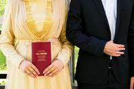Close-up of a bride and groom holding a marriage certificate, showcasing Turkish wedding attire.