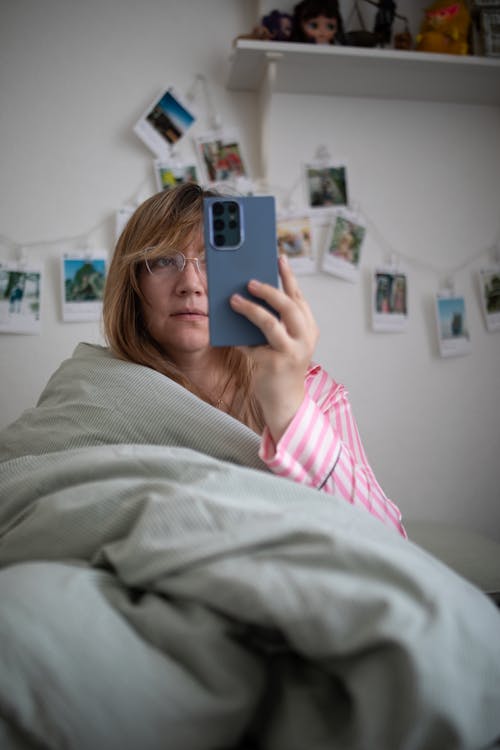 Free Woman in Bed Holding Smartphone Stock Photo