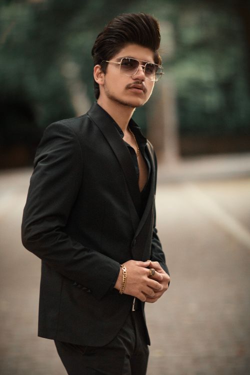 Free Sophisticated man posing confidently in a sleek black suit outdoors. Stock Photo