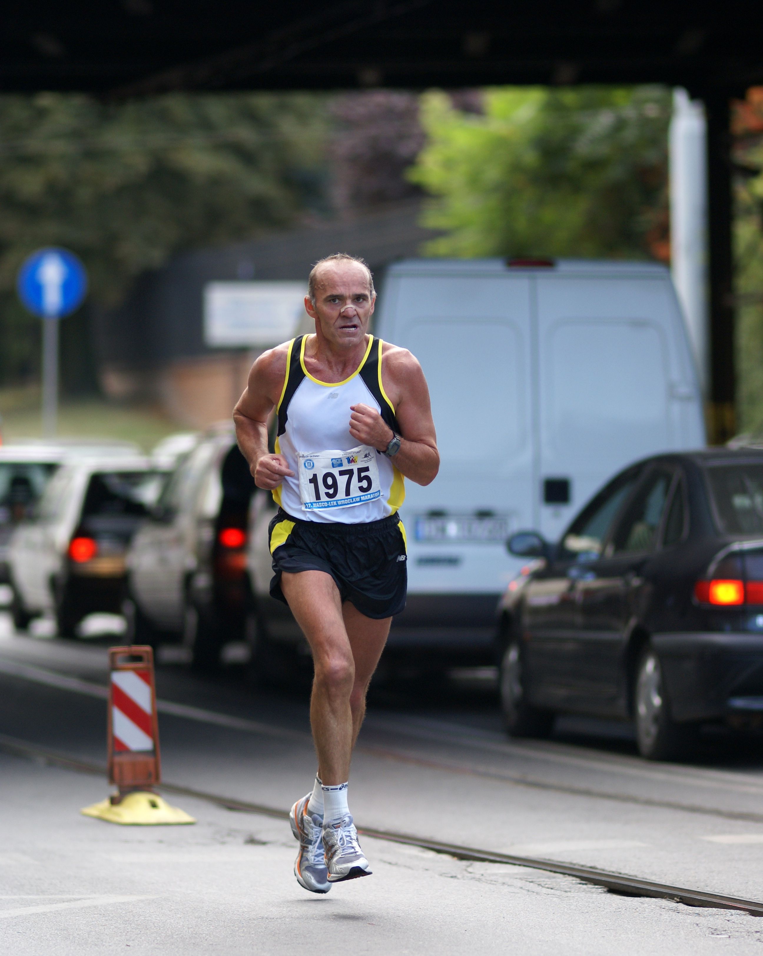 A man running in a marathon race under a street · Free Stock Photo