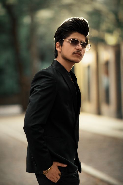 Free Fashionable young man posing confidently outdoors in a city setting. Stock Photo