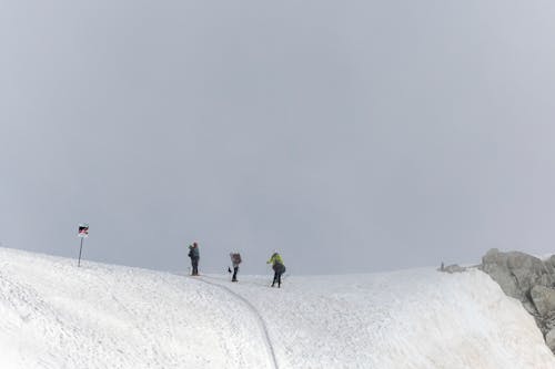 View of People Standing at the Peak of a Snowy Mountain 