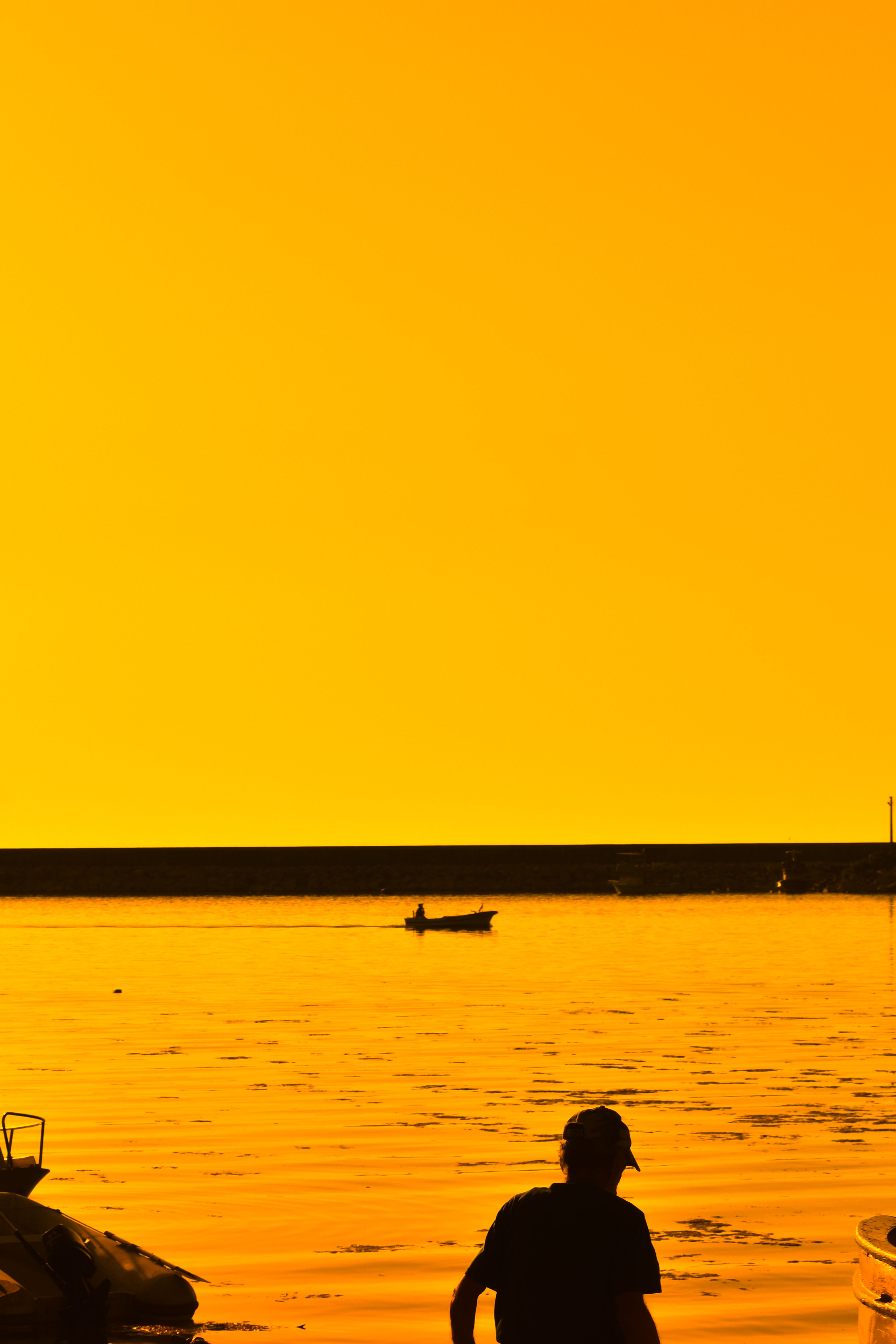 Silhouette of a Man Standing near a Shore at Sunset · Free Stock Photo