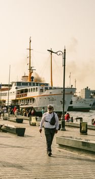A vibrant view of a harbor in Istanbul with a ferry and people walking, capturing the essence of urban life.