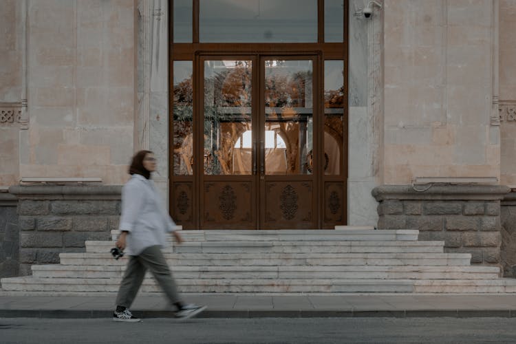 Woman In Hijab Walking Near Building Stairs And Door