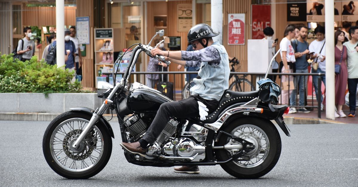 Um homem anda em uma motocicleta preta estilosa em uma rua movimentada da cidade, capturando a vida urbana.