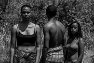 Artistic black and white photo of three adults outdoors, capturing emotion and unity.