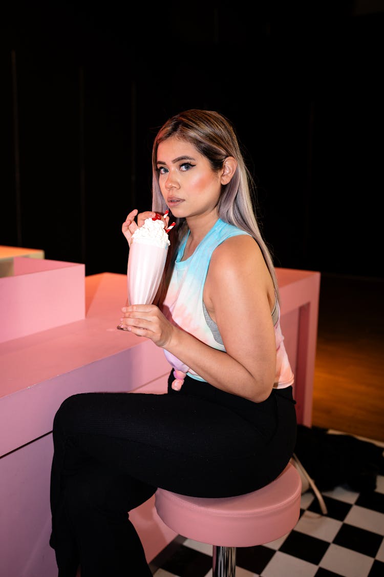 Young Woman Sitting At The Counter And Drinking A Milkshake 