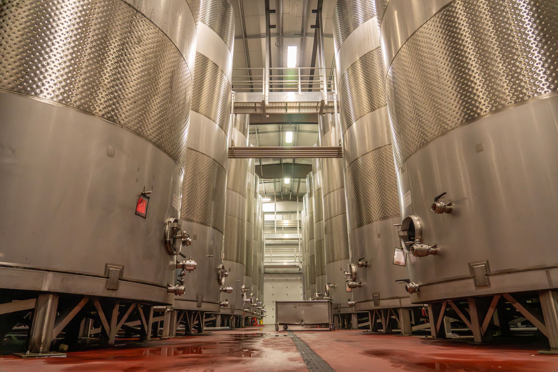 Interior of an industrial brewery with large, stainless steel fermentation tanks.
