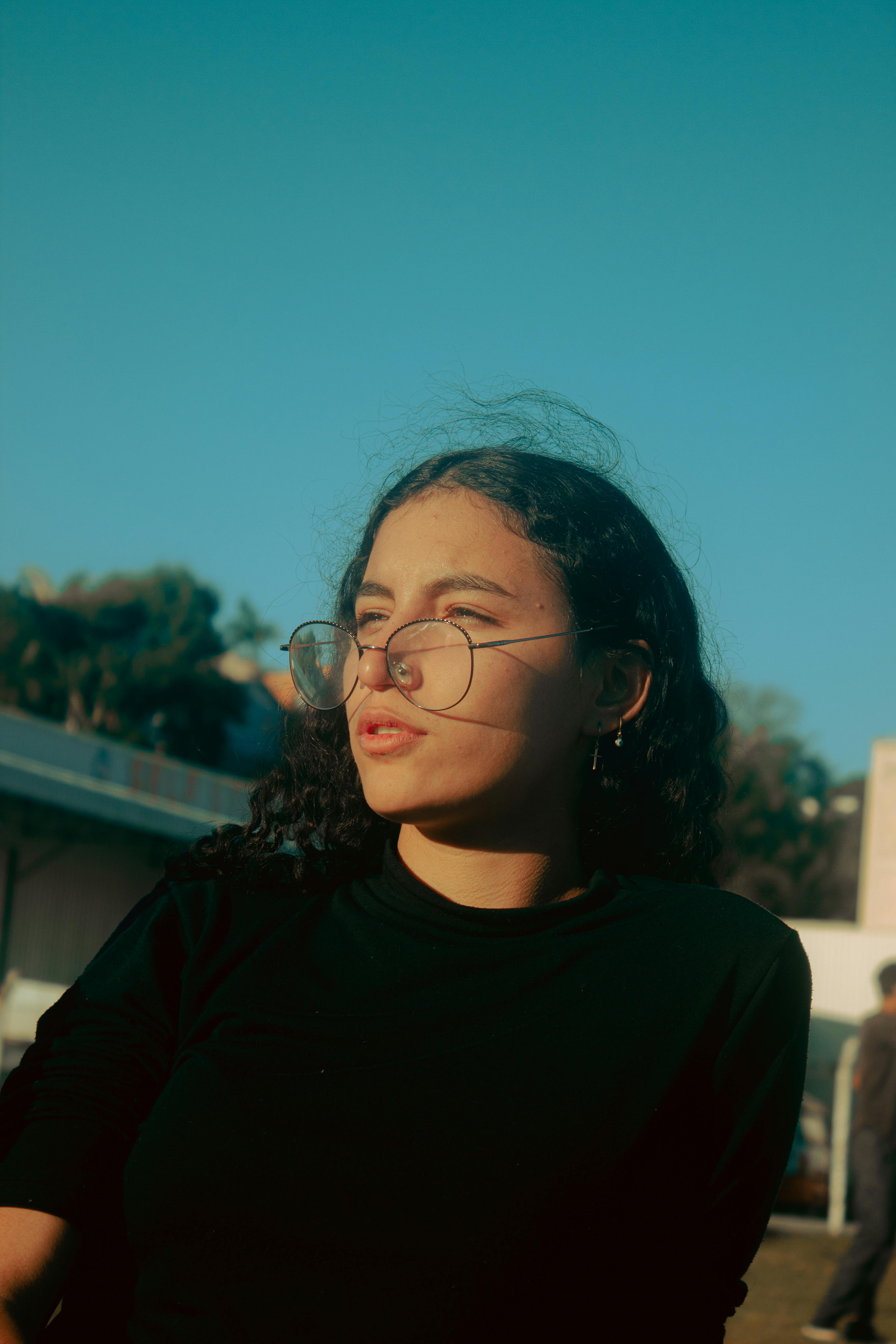 Sunlit outdoor portrait of a woman with eyeglasses enjoying the day.