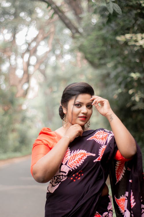 Young Woman in a Sari Standing on a Road near Trees