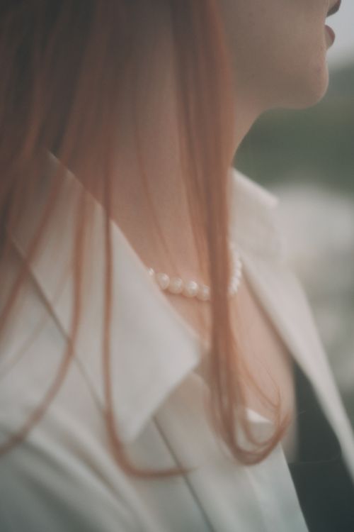 Free Soft focus close-up of a redhead wearing a pearl necklace, capturing elegance and simplicity. Stock Photo