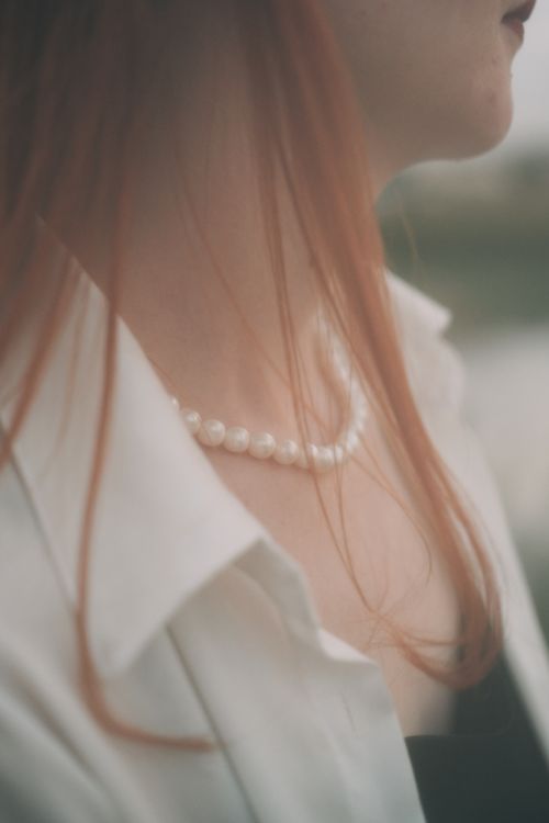 Free Close-up of a woman's neck with a pearl necklace and red hair. Stock Photo