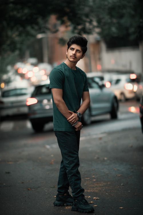 Free Young male model posing stylishly on an urban street with blurred traffic in the background. Stock Photo