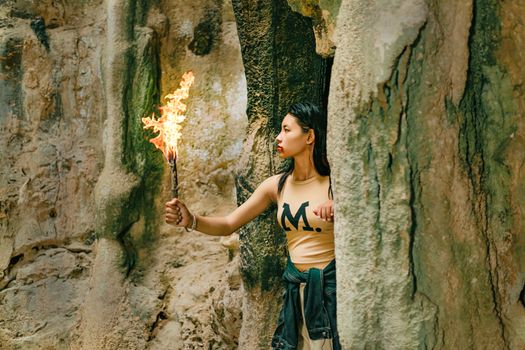 Young woman exploring a cave with a fiery torch.