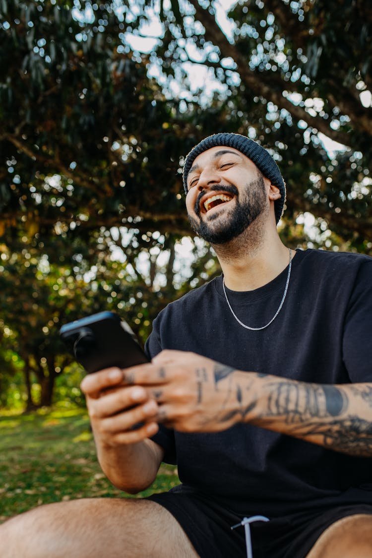 Portrait Of A Bearded Man Laughing With A Smart Phone In Hands