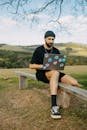Man Sitting with Laptop on Wooden Bench on Meadow under Tree