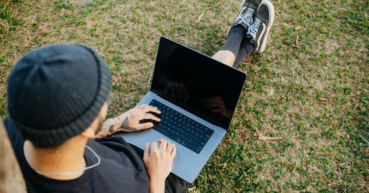 a person using a laptop surrounded by vintage tech and printed out forum threads