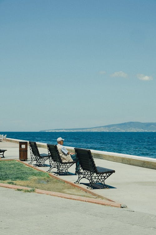 Elderly Man Sitting on a Bench on the Seashore 