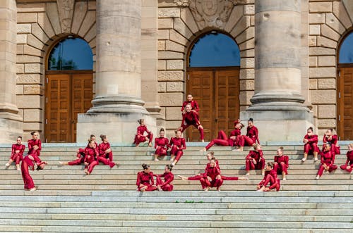 Gymnasts in Red Clothes on Stairs of Building