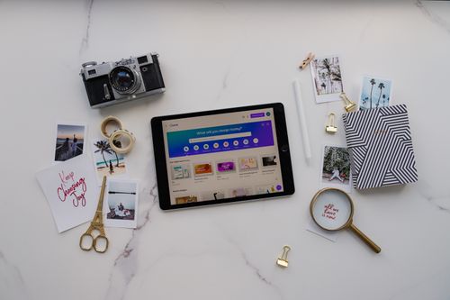 Free Modern creative workspace featuring a tablet, photos, and vintage camera on a marble background. Stock Photo