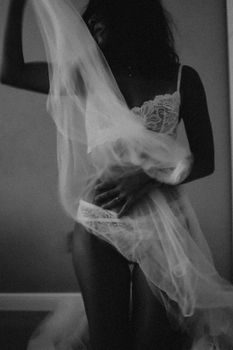 Elegant black and white portrait of a woman posing in lingerie draped in sheer fabric.