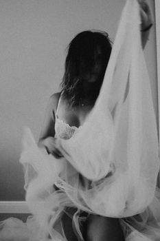 Artistic black and white photo of a woman in lace lingerie, captured in motion.