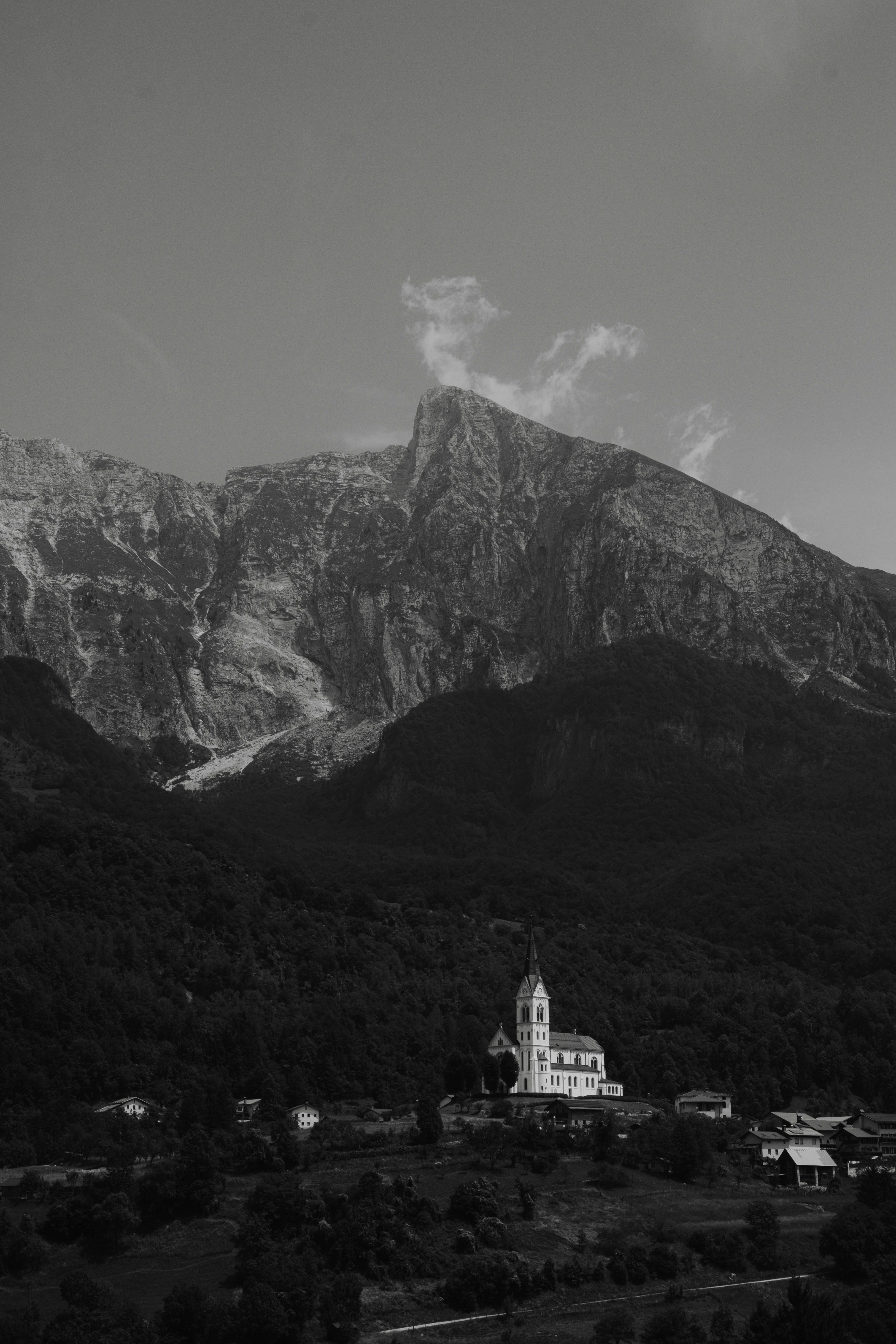 A picturesque church nestled in a valley with towering mountains in the background.