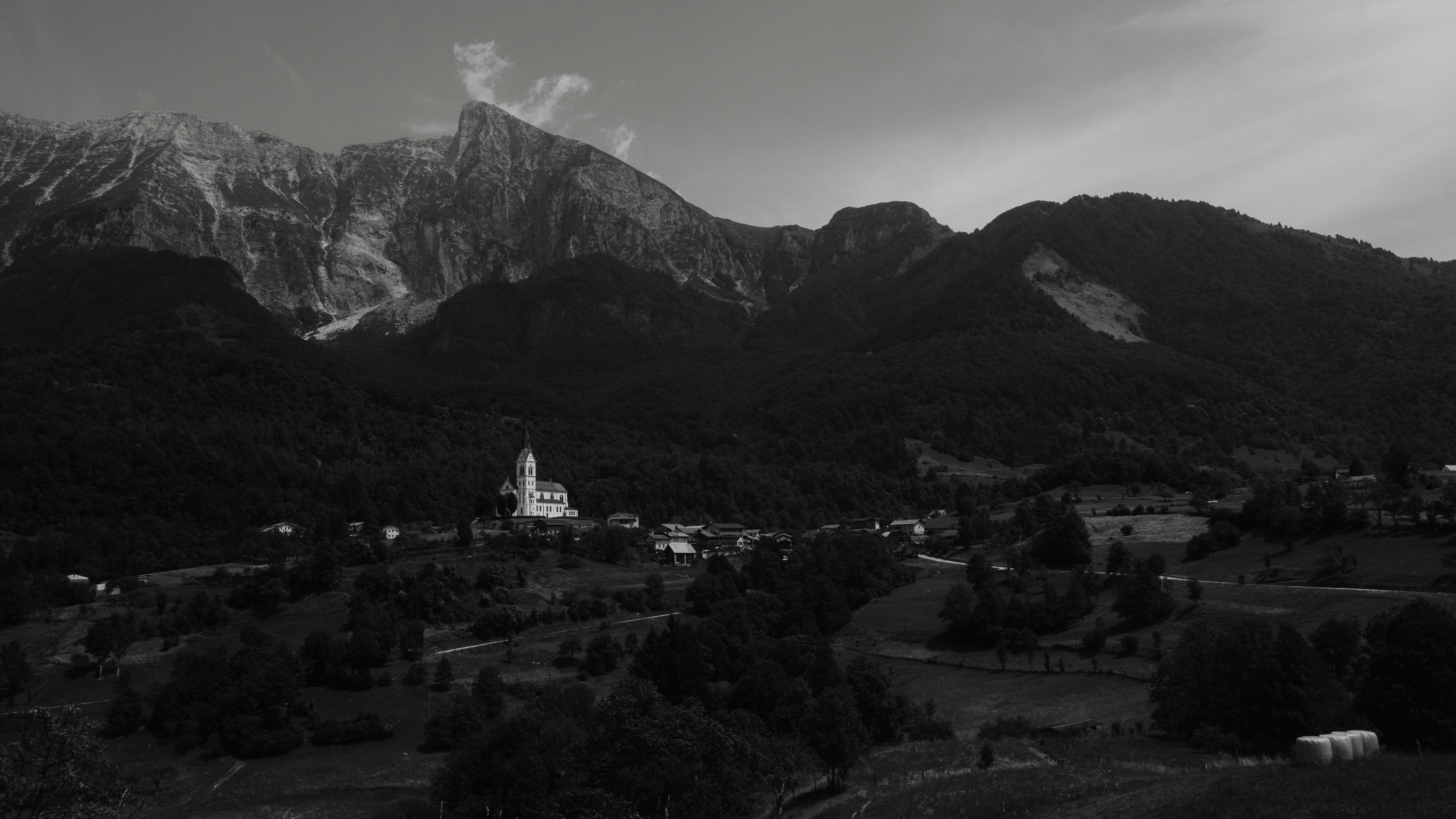 Scenic monochrome view of a mountain village nestled under towering peaks in a rural setting.