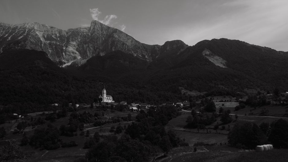 Scenic monochrome view of a mountain village nestled under towering peaks in a rural setting.