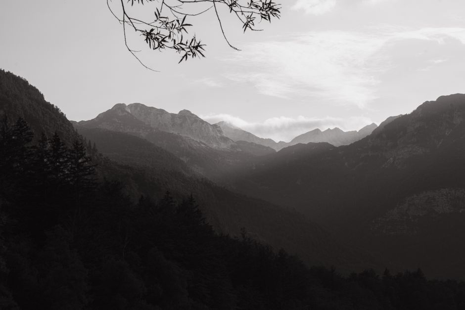 Dramatic black and white view of mountain ranges enveloped in mist, creating a tranquil atmosphere.