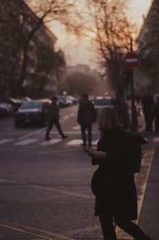 Silhouette of a woman crossing a street in Baku during an autumn sunset. Moody and atmospheric.
