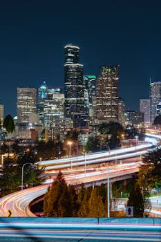 Captivating night view of Seattle's skyline with vibrant light trails and skyscrapers.