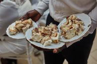 Close-up of a man holding plates with dessert cakes ready to serve at a social event in Cameroon.