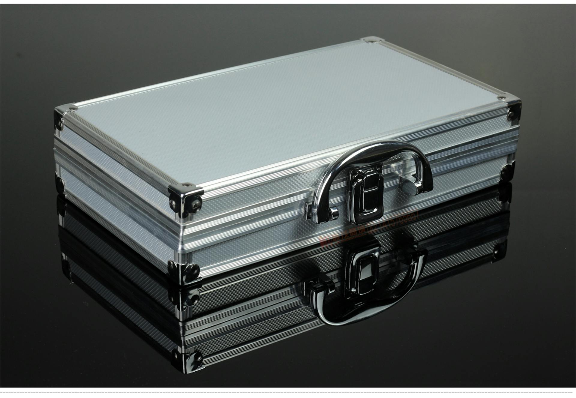 Shiny metallic briefcase with a sleek chrome finish and clear reflection on black surface.