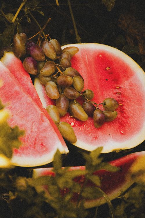 Free Juicy watermelon slices with ripe grapes in a natural outdoor setting. Perfect for summer themes. Stock Photo
